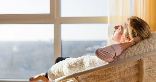 Person relaxing in a warm modern room with invisible infrared heating, showing natural sunshine-like comfort without harmful UV.
